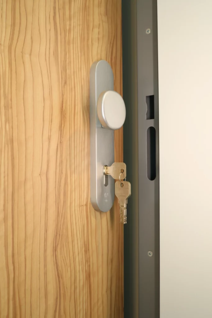 Veiligheidsbeslag met cilinder en sleutels op een houten deur